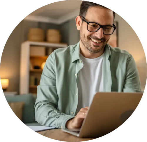 A man at his desk smiling at his computer