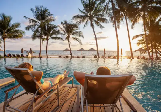 Couple relaxing by pool and palm trees