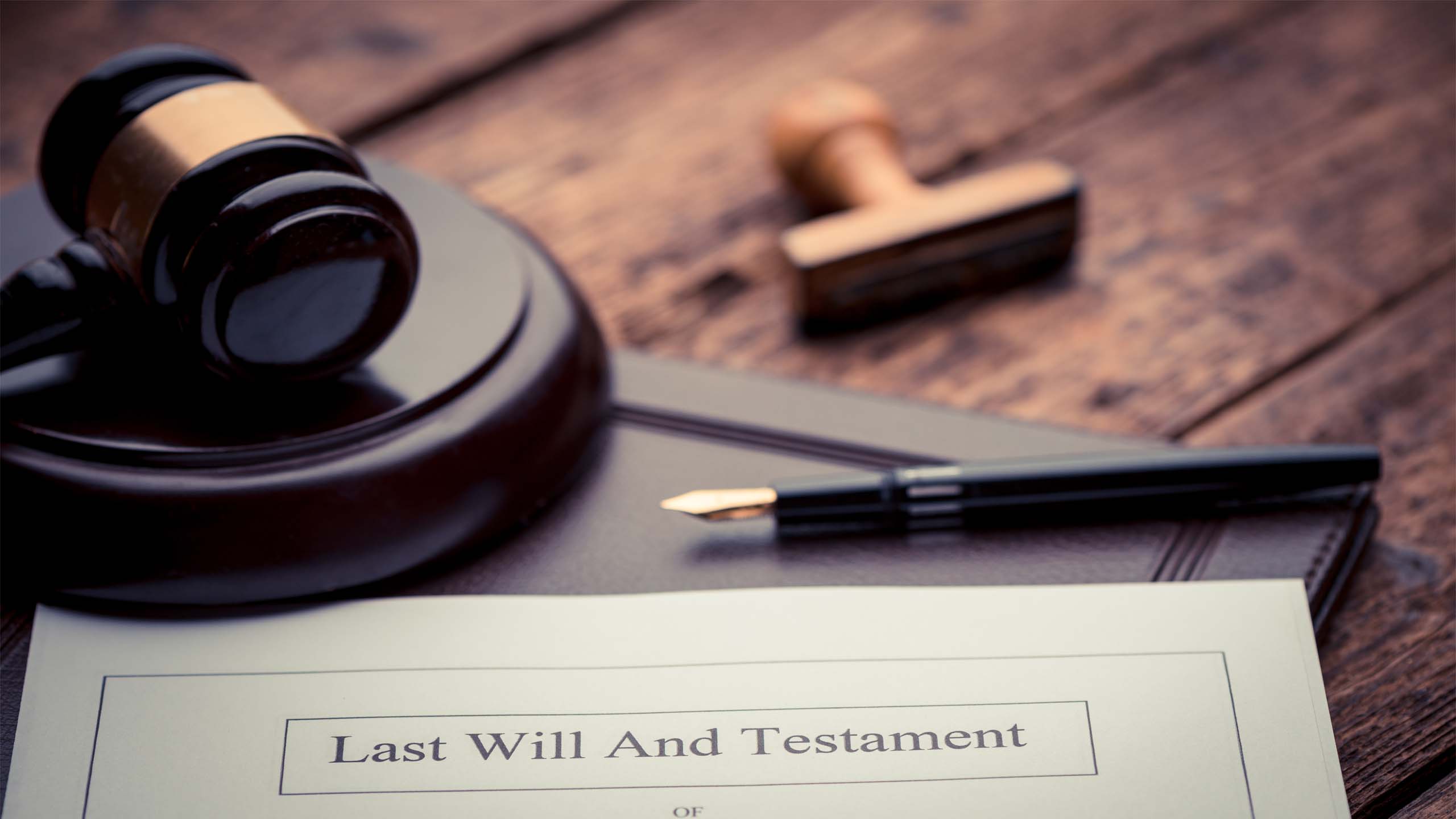 Gavel and pen with words last will and testament written on document
